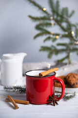 Obraz na płótnie Canvas Christmas tea with cinnamon and spices in a red mug with homemade cookies on a gray background with a Christmas tree and a garland