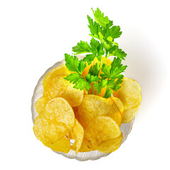 Potato chips with parsley flavor in a transparent glass bowl isolated on white background, top view.