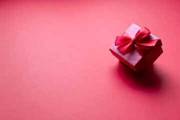 on a red background hanging a red box with a gift red bow