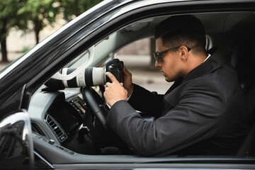 Private detective with camera spying from car