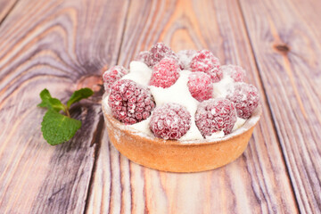 One raspberry tartlet on a wooden table.