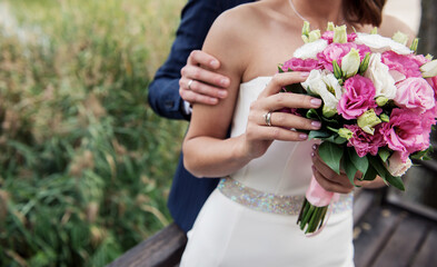 bride holding wedding bouquet , 
hands of a young woman with wedding rings
