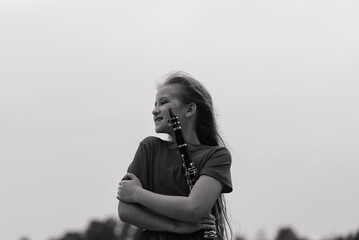 Young attractive girl playing clarinet, ebony in fall park
