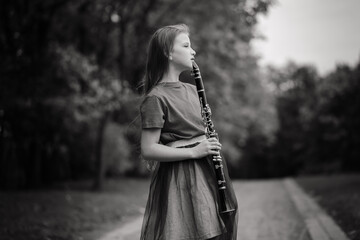 Young attractive girl playing clarinet, ebony in fall park