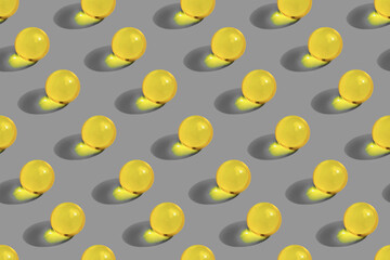 Round yellow pills on gray background pattern. Organic nutrition, vitamin, oil. Skincare beauty supplement.