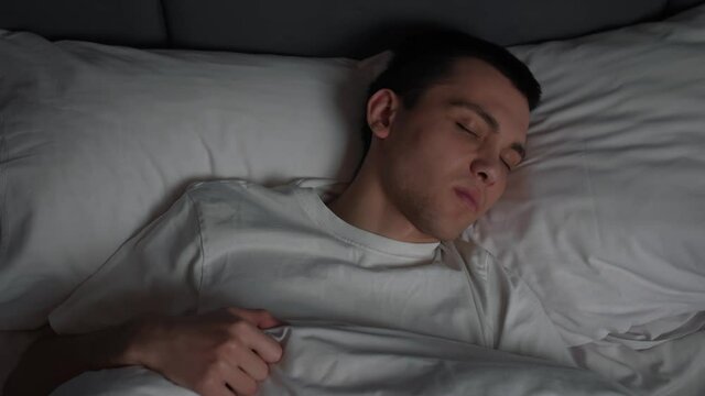 Top View of Man Trouble Sleeping in Loft Bedroom. Beautiful Young Man Having Bad dream. man with Insomnia. Sleeping Disorder.