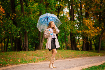 Young attractive smiling girl under umbrella in autumn forest