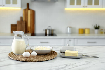 Different dairy products and eggs on white table in modern kitchen. Space for text