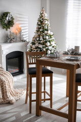 Festive table setting and beautiful Christmas decor in living room. Interior design