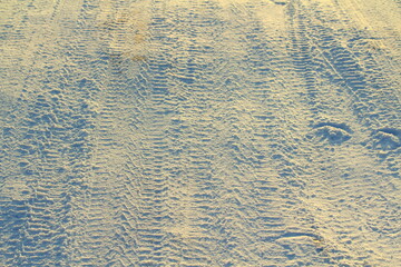 Tire tracks left in the snow on a bright sunny day