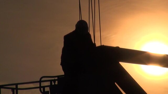 Unrecognizable construction worker showing cran operater what to do at sunset.