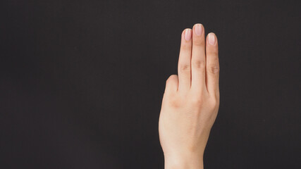 Fototapeta premium A hand sign of 3 fingers point upward meaning three, third or use in protest.It put on black backgroud.
