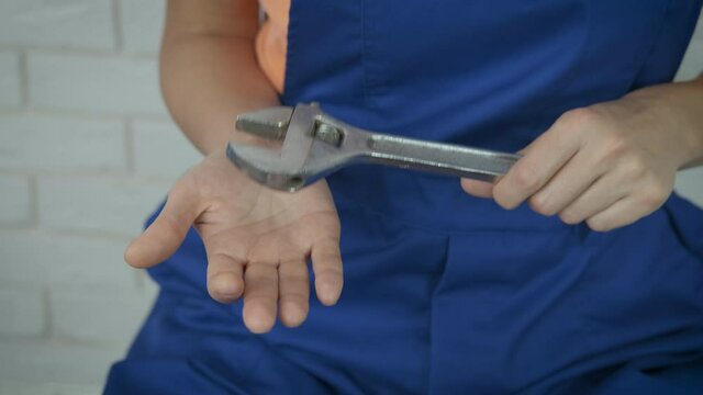 Hold a spanner in hands. Female hands with a large adjustable wrench.