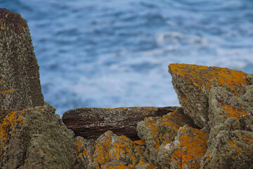 Lichen covered rocks forming a natural frame with blue sea in the background