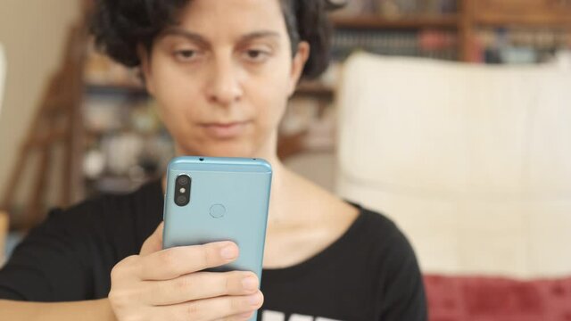 Smartphone. Young adult woman holding mobile phone technology device indoors 4K. Young girl exhausted by internet social media.