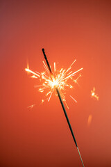 A burning sparkler on a colorful background
