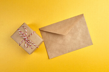 Craft paper envelope and gift box on golden background