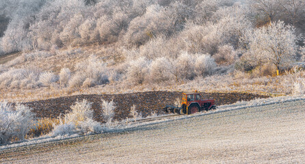 Early winter countryside agriculture tractor in the field frozen vegetation 