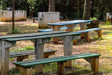 Bancos e mesa de madeira vazios e abandonados dentro de parque 