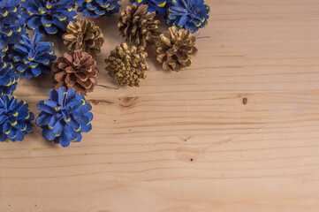 several small pine cones painted blue and golden, isolated on wooden background