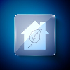 White Eco friendly house icon isolated on blue background. Eco house with leaf. Square glass panels. Vector.