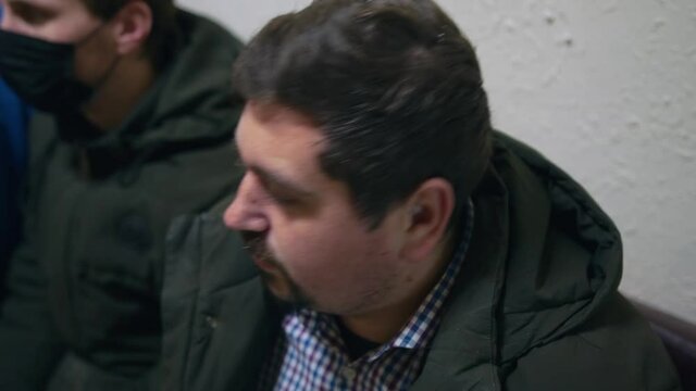 The man sits in line and can not wait for the reception and with hope in big bulging eyes suddenly and quickly raises his head up and looks at the wall clock and with disappointment lowers his head