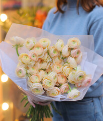 Young woman florist holding big beautiful blossoming mono bouquet of yellow ranunculus clooney hanoi flowers.