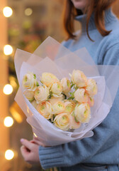 Young woman florist holding big beautiful blossoming mono bouquet of yellow ranunculus clooney...