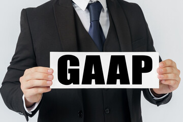 A businessman holds a sign in his hands which says GAAP