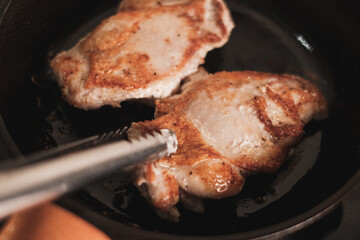 Juicy whole chicken breasts searing  in a cast iron skillet.