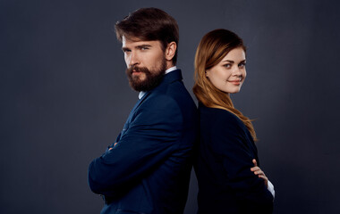 successful people in suits stand with their backs to each other on gray background business finance