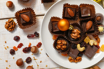 sweet food background for christmas or holiday decoration - chocolate candies, tangerines, nuts and dried fruits on white wood