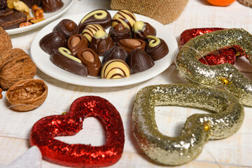 sweet food background for christmas or holiday decoration - chocolate candies, tangerines, nuts and dried fruits on white wood