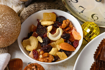sweet food background for christmas or holiday decoration - chocolate candies, tangerines, nuts and dried fruits on white wood