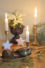Christmas balls, white poinsettia and three burning candles during the Advent period
