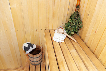 Interior details Finnish sauna steam room with traditional sauna accessories basin birch broom scoop felt hat towel. Traditional old Russian bathhouse SPA Concept. Relax country village bath concept.