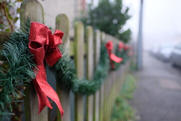 Wooden fence decorated in a festive style with red ribbons as the december and christmas time approaches