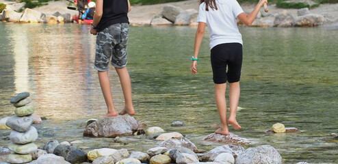 Couple of people walking on the rocks by the river and a tower of rocks