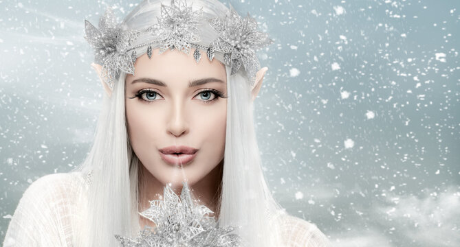 Winter queen. Gorgeous woman with snow queen costume blowing magic icy air. Fairy concept for xmas