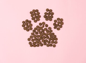Dry food in the form of a paw on a pink background with a place for text.