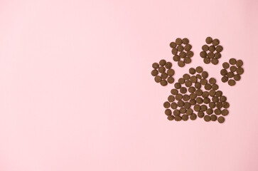 Dry food in the form of a paw on a pink background with a place for text.