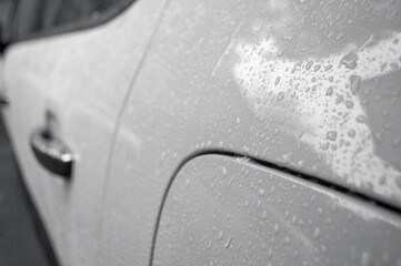 Beautiful rain drops on the car of trendy gray color. Wet car body of trendy gray color. Colou of the year concept.