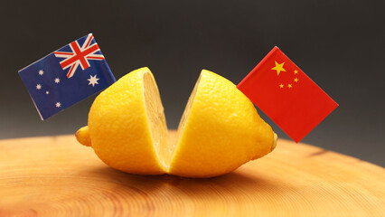 Australian and Chinese flags stuck in a sliced lemon on a chopping block representing the strained...