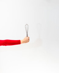 Hand holding a whisk for cooking on a white background.