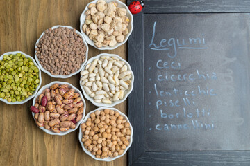 A selection of dried legumes with the names written in Italian on the blackboard