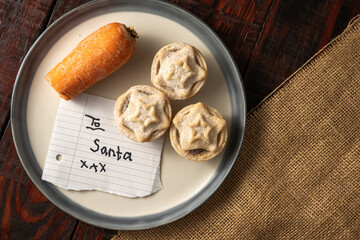 Carrot and yummy mince pies on a dish with a note "To Santa", a Christmas treat for Santa Claus © Max Rushent/Wirestock