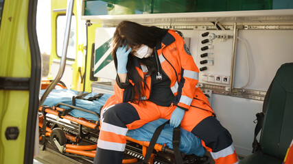 Exhausted female paramedic in face mask makes face palm