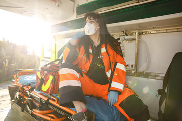 Young female paramedic sits in emergency vehicle