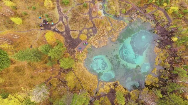 Geyser Blue Lake and Yellow Trees in Autumn. Aerial Top-Down View. Altai Republic, Russia. Drone Flies Sideways