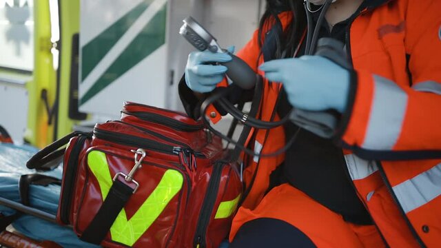 Female paramedic checks manometer sitting inside an emergency vehicle